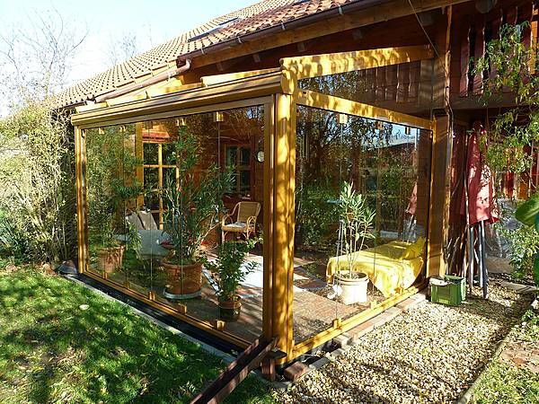 Moderner Wintergarten aus Glas mit Holzkonstruktion und vielen Pflanzen am Haus.