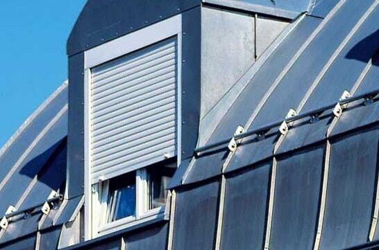 Dachfenster mit geschlossenem Rollladen an modernem Metall-Dach für Wärmeschutz.